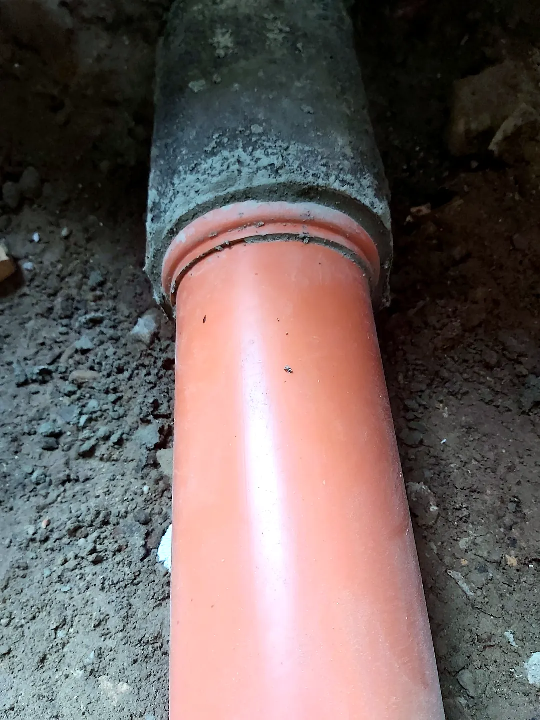 Narancssárga csatornacső csatlakozik a betoncsőhöz a földben